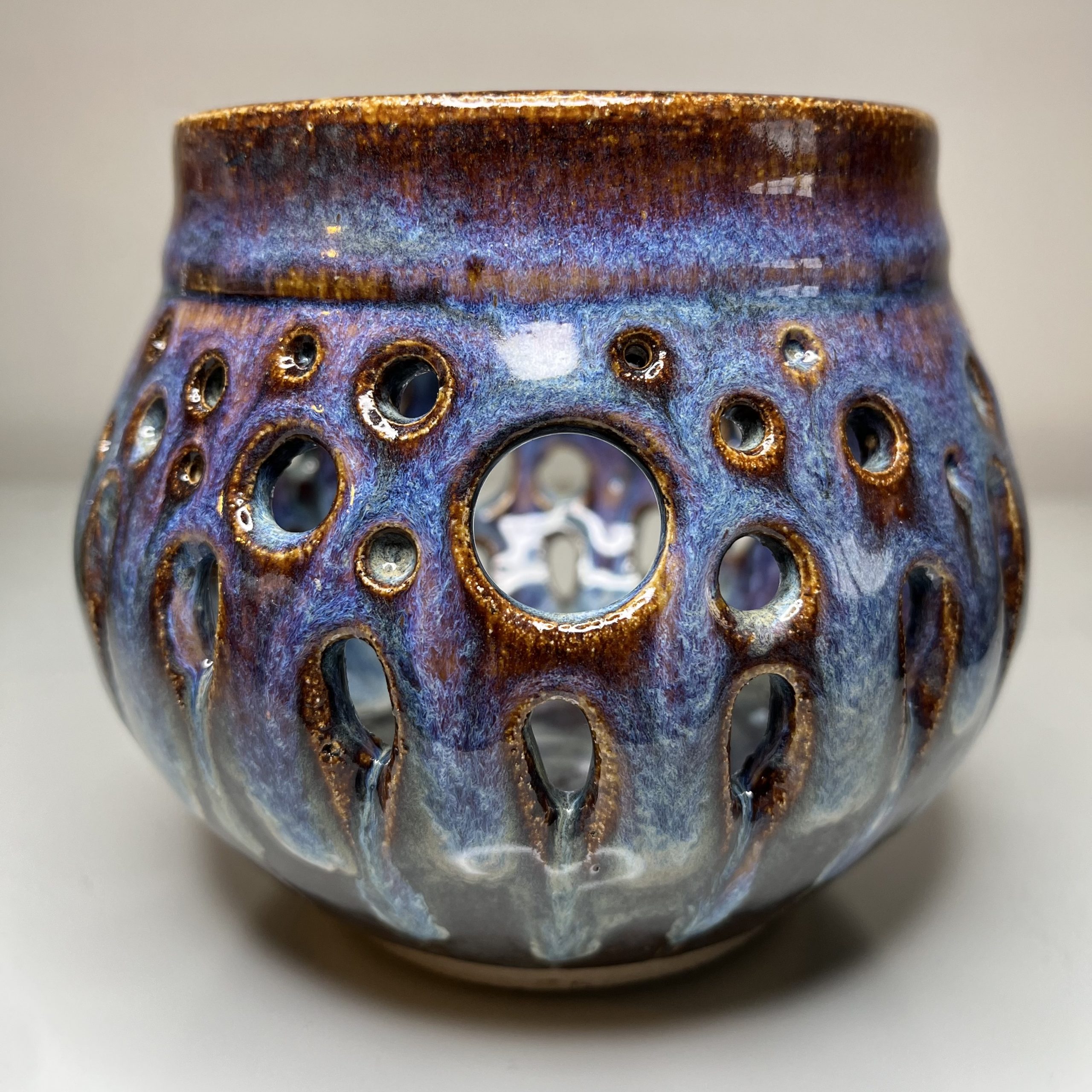 spherical hand thrown pot with hole for a tea light. Representing bubbles. Glossy blues and purples