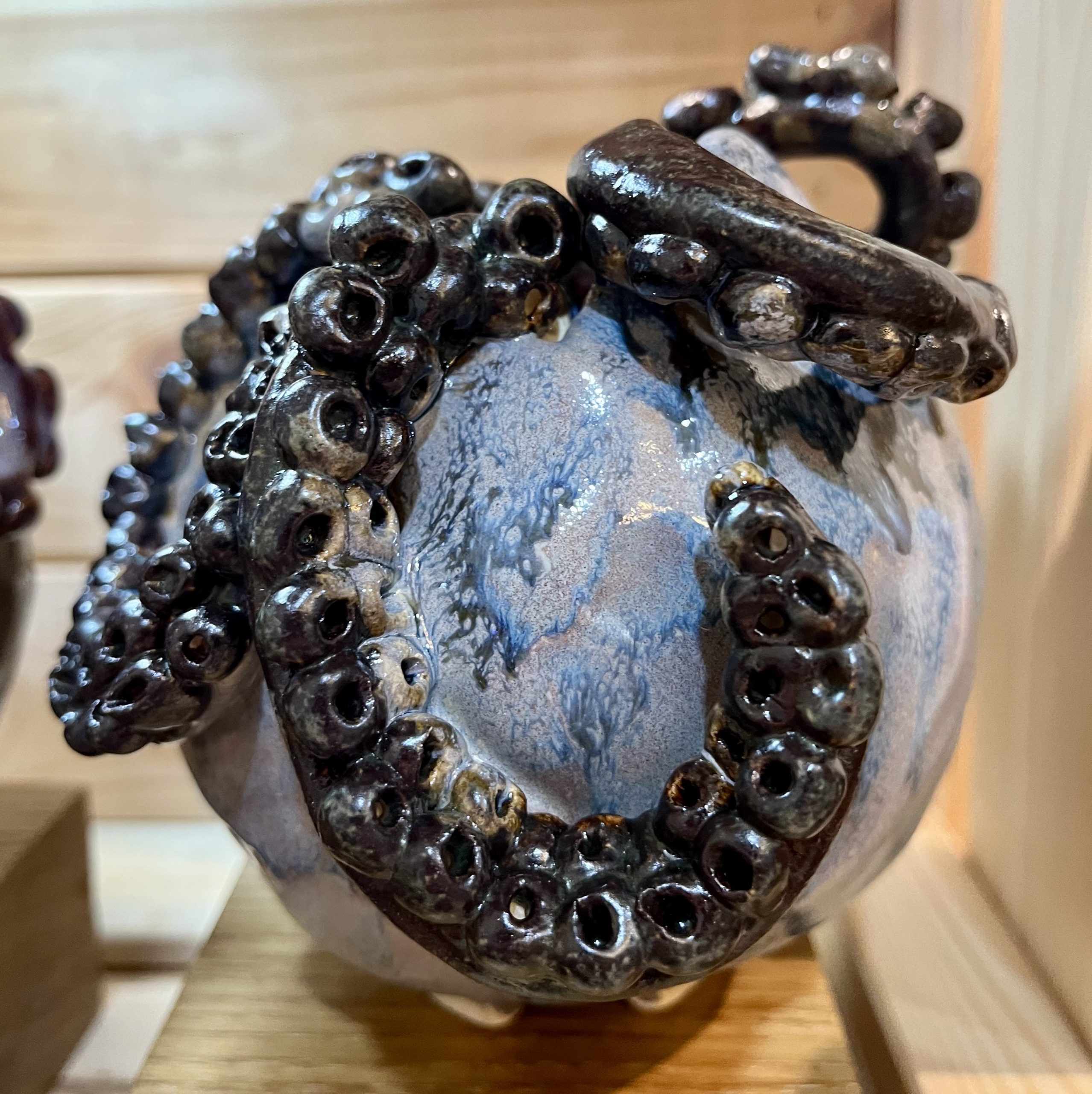 Blue pot with black pot with tentacles coming out of the top